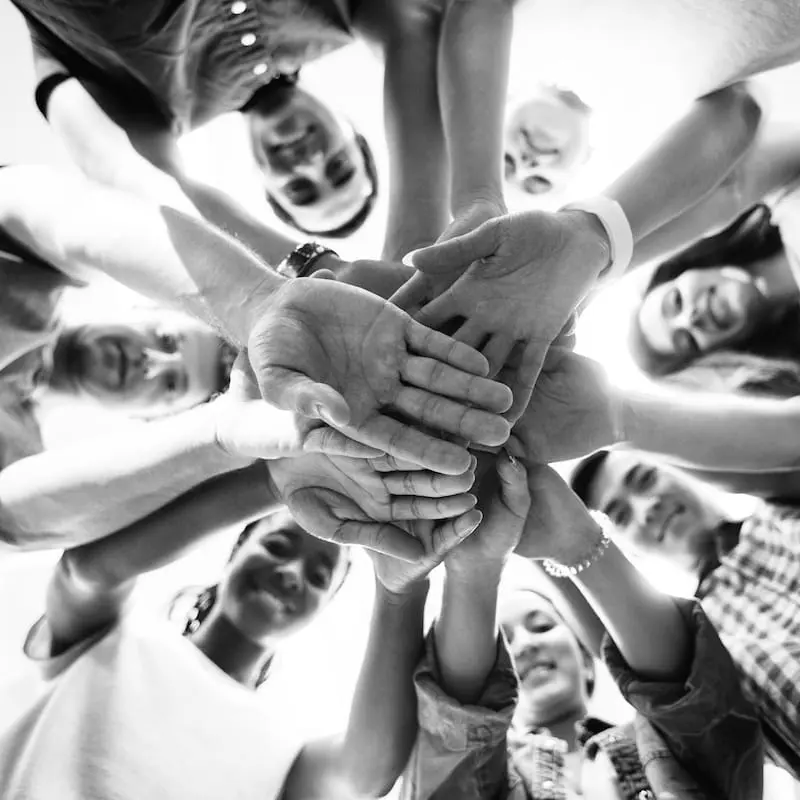 Perspektiven verbinden – Gemeinsames Verständnis und Resonanz Mehrere Personen legen ihre Hände zusammen als Symbol für gemeinsames Verständnis, Perspektivenvielfalt und erfolgreiche Zusammenarbeit.