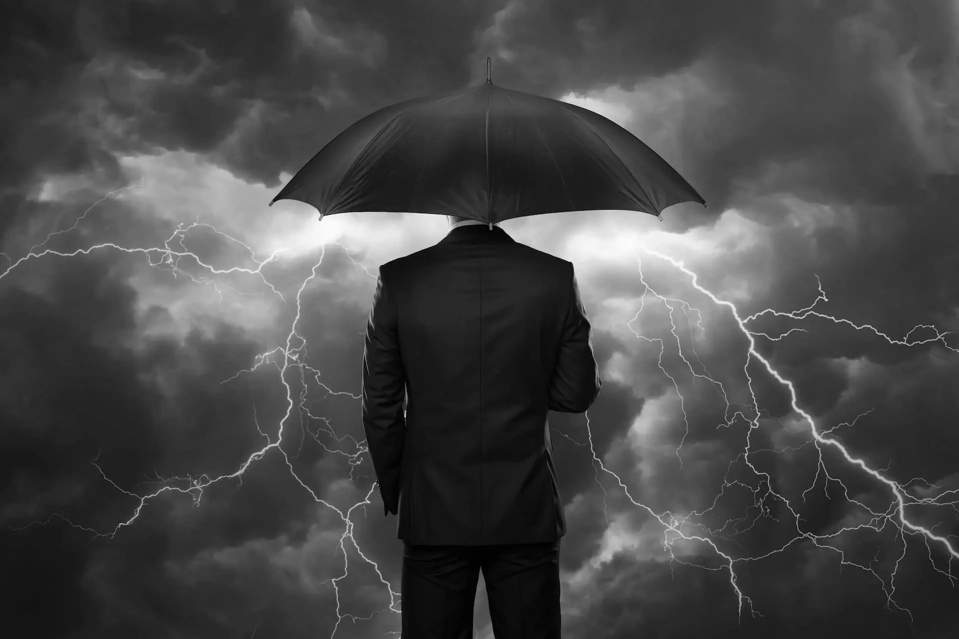 Person steht mit einem Regenschirm unter einem Gewitter als Symbol für Risikofrüherkennung, Krisenprävention und nachhaltige Sicherheit im Unternehmen.