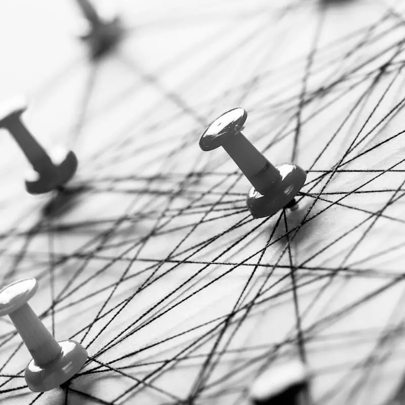 Vernetzte Stecknadeln und Verbindungslinien als Symbol für Ursachenanalyse, Zusammenhänge und Transparenz in komplexen Organisationen.