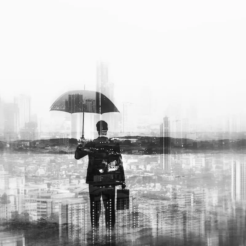 Unternehmerische Standortbestimmung | Klarheit und Entscheidungssicherheit Person mit Regenschirm vor einer abstrahierten Stadtkulisse als Symbol für Orientierung, Klarheit und unternehmerische Standortbestimmung.