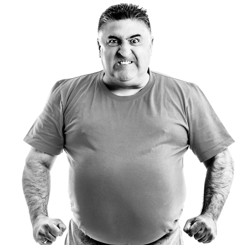 Wenn Probleme im System entstehen und Menschen die Konsequenzen tragen Person steht mit verschränkter Körperspannung vor hellem Hintergrund. Das Bild symbolisiert Frustration, Belastung und die Auswirkungen von Störungen in Kommunikation, Führung und Wertschöpfungsprozessen.