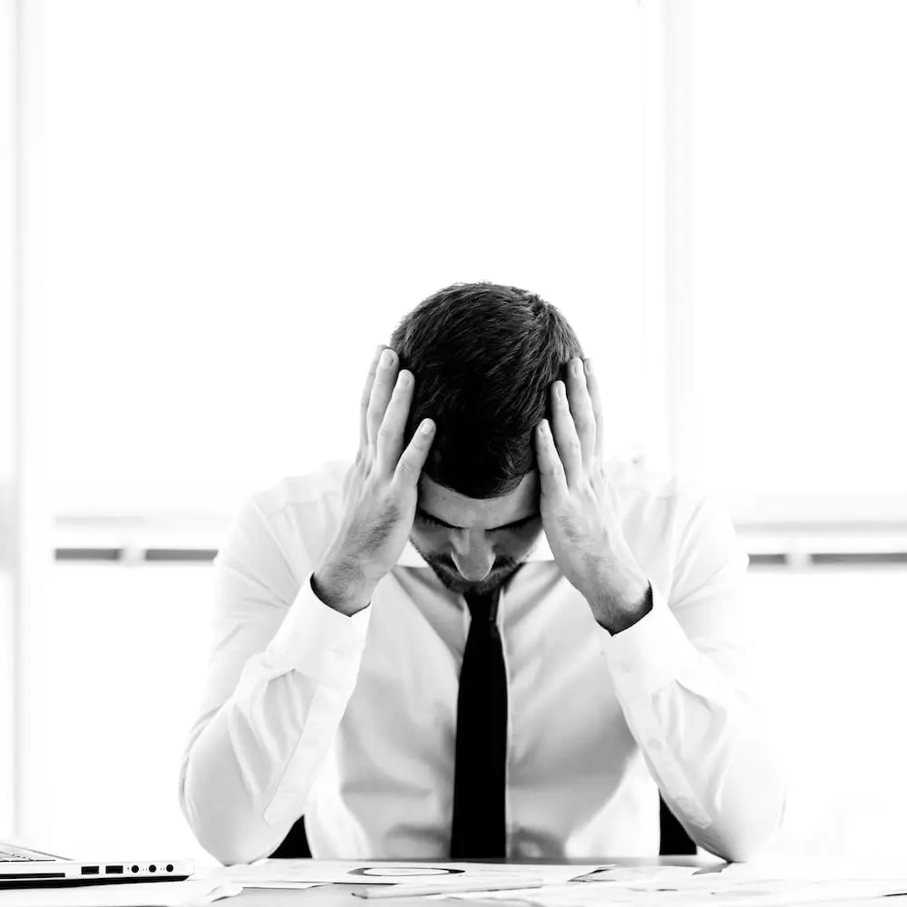 Wenn intensives Nachdenken keine neuen Antworten mehr liefert Person sitzt an einem Schreibtisch und stützt den Kopf mit beiden Händen. Das Bild symbolisiert Entscheidungsdruck, Überforderung und den Verlust von Orientierung im beruflichen Kontext.